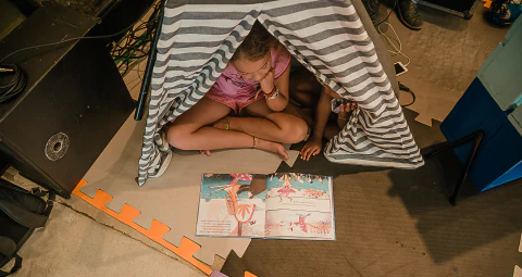 Criança dentro de uma cabana lendo
